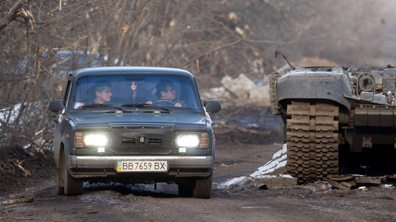 Donbass-Region: Ukrainische Zivilisten fahren an einem zerstörten T-72 Panzer vorbei.