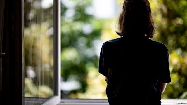 Eine Frau steht in ihrer Wohnung an einem Fenster (Symbolbild): Häusliche Gewalt nimmt an Feiertagen zu.