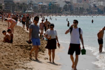Touristen laufen am Strand von Arenal, Palma (Symbolbild): Der Tourismus ist ein entscheidender Wirtschaftsfaktor auf Mallorca.