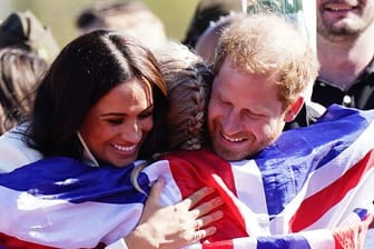 Prinz Harry (r) und Meghan (l) umarmen die britische Teilnehmerin Lisa Johnston.