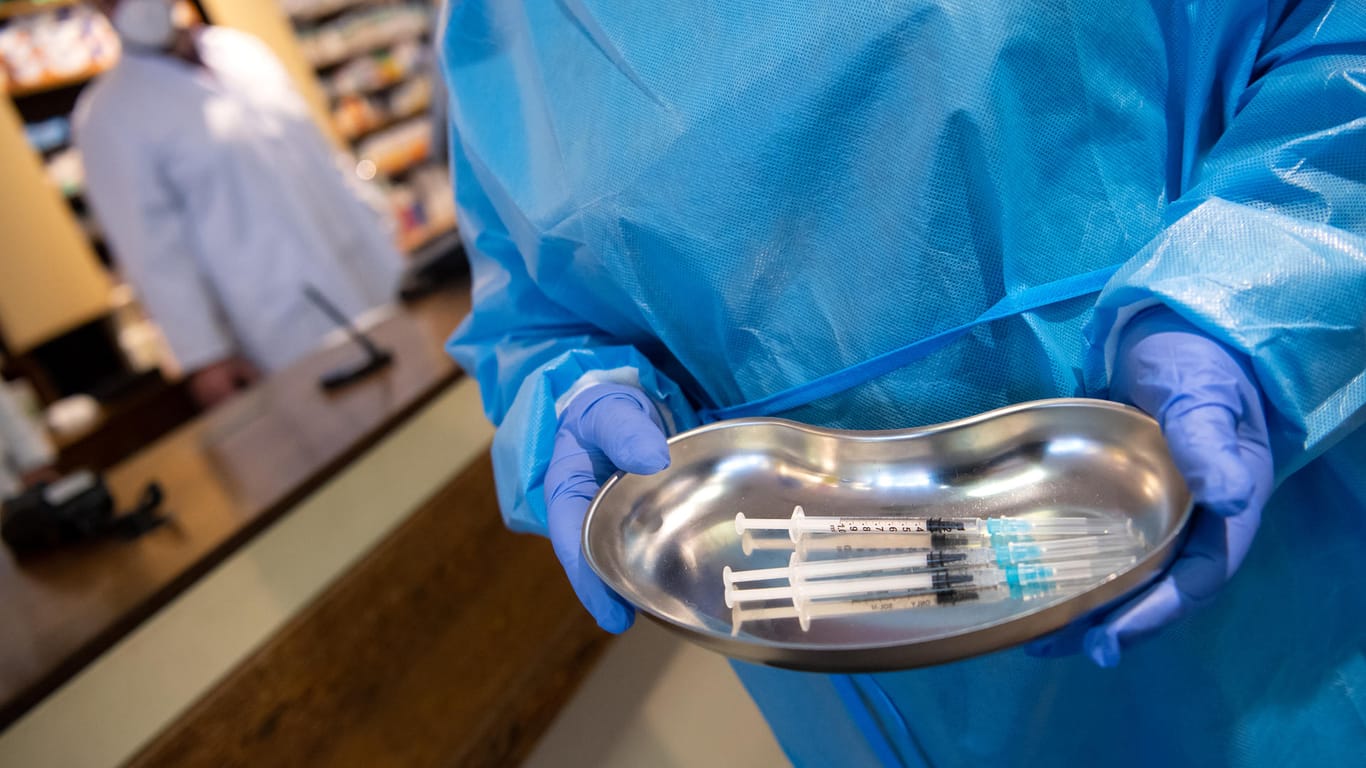 Eine Krankenpflegerin steht mit Spritzen in einer Schale in einer Apotheke (Symbolbild): Noch sind weitere Auffrischungsimpfungen in Deutschland nötig.