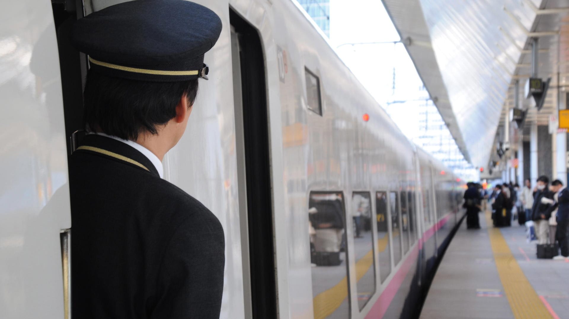 Ein Zugbegleiter schaut aus der Tür eines Hochgeschwindigkeitszugs Shinkansen: Nicht nur Verspätungen sind in bei Japans Bahnen verpönt, auch zu frühes Abfahren. Ein Zugbegleiter schaut aus der Tür eines Hochgeschwindigkeitszugs Shinkansen: Nicht nur Verspätungen sind in bei Japans Bahnen verpönt, auch zu frühes Abfahren.