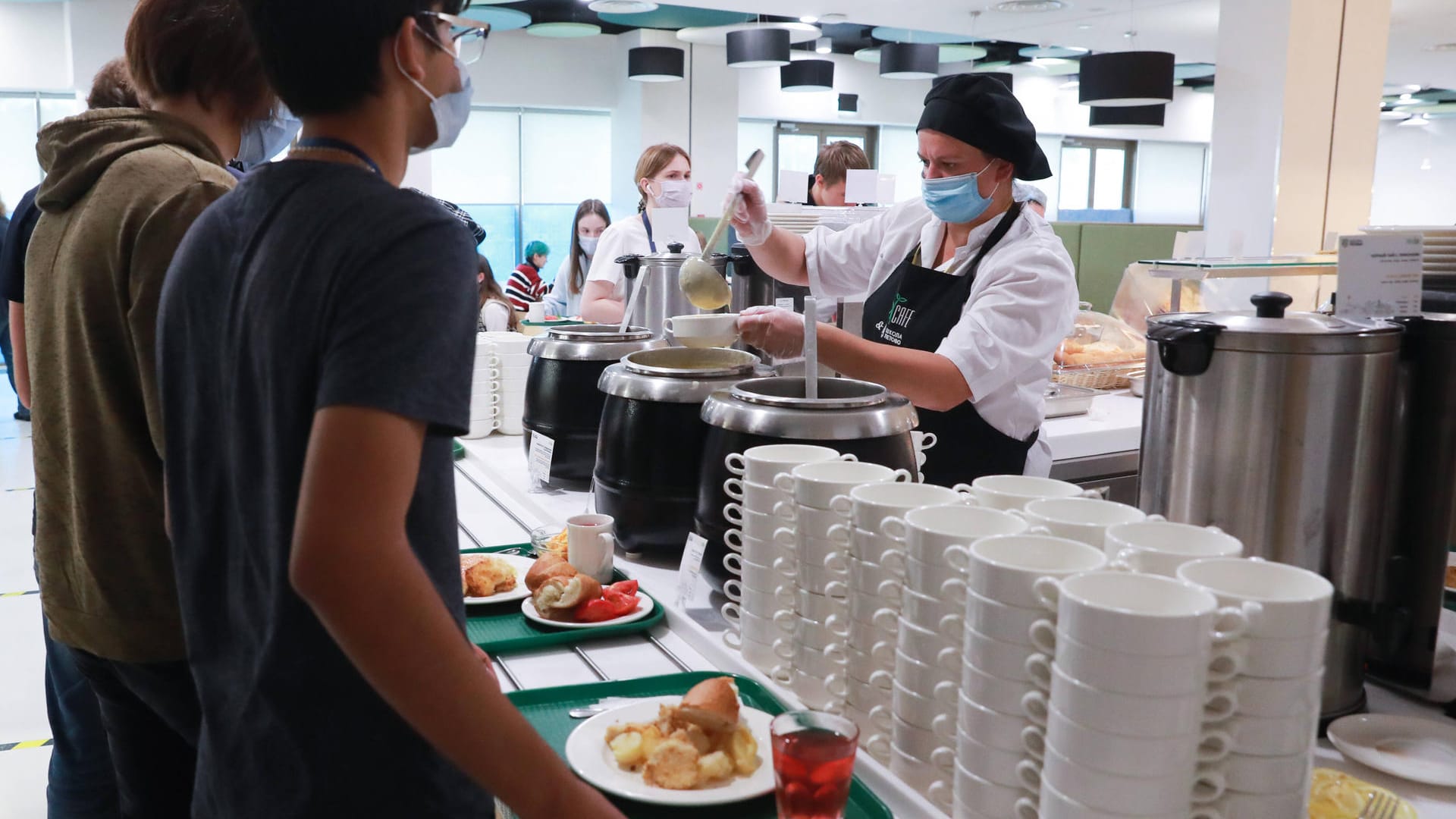 Mitarbeiterin serviert Schülern Essen (Symbolbild): Die Grünen wollen günstigeres Essen in Schulen einführen. Mitarbeiterin serviert Schülern Essen (Symbolbild): Die Grünen wollen günstigeres Essen in Schulen einführen.