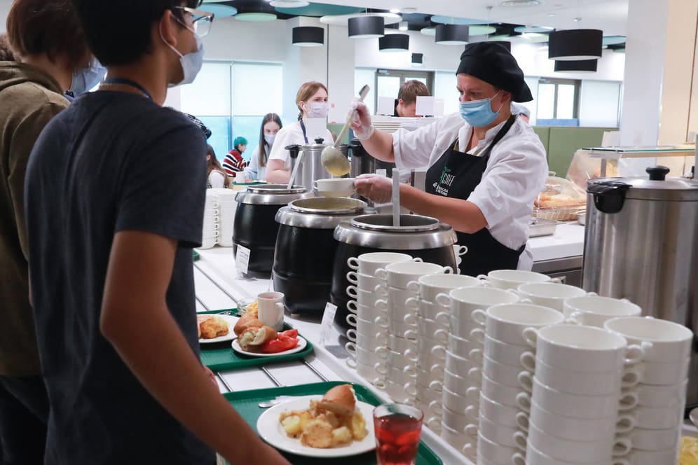 Mitarbeiterin serviert Schülern Essen (Symbolbild): Die Grünen wollen günstigeres Essen in Schulen einführen.