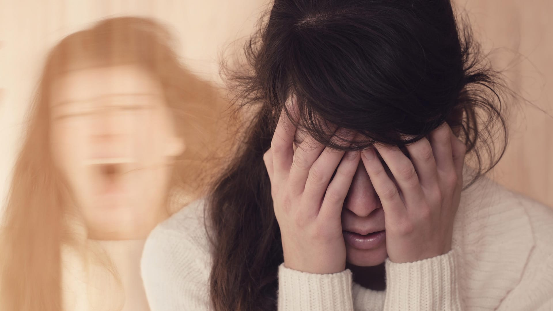 Junge Frau hält sich die Augen zu, im Hintergrund der Schatten einer schreienden Frau.