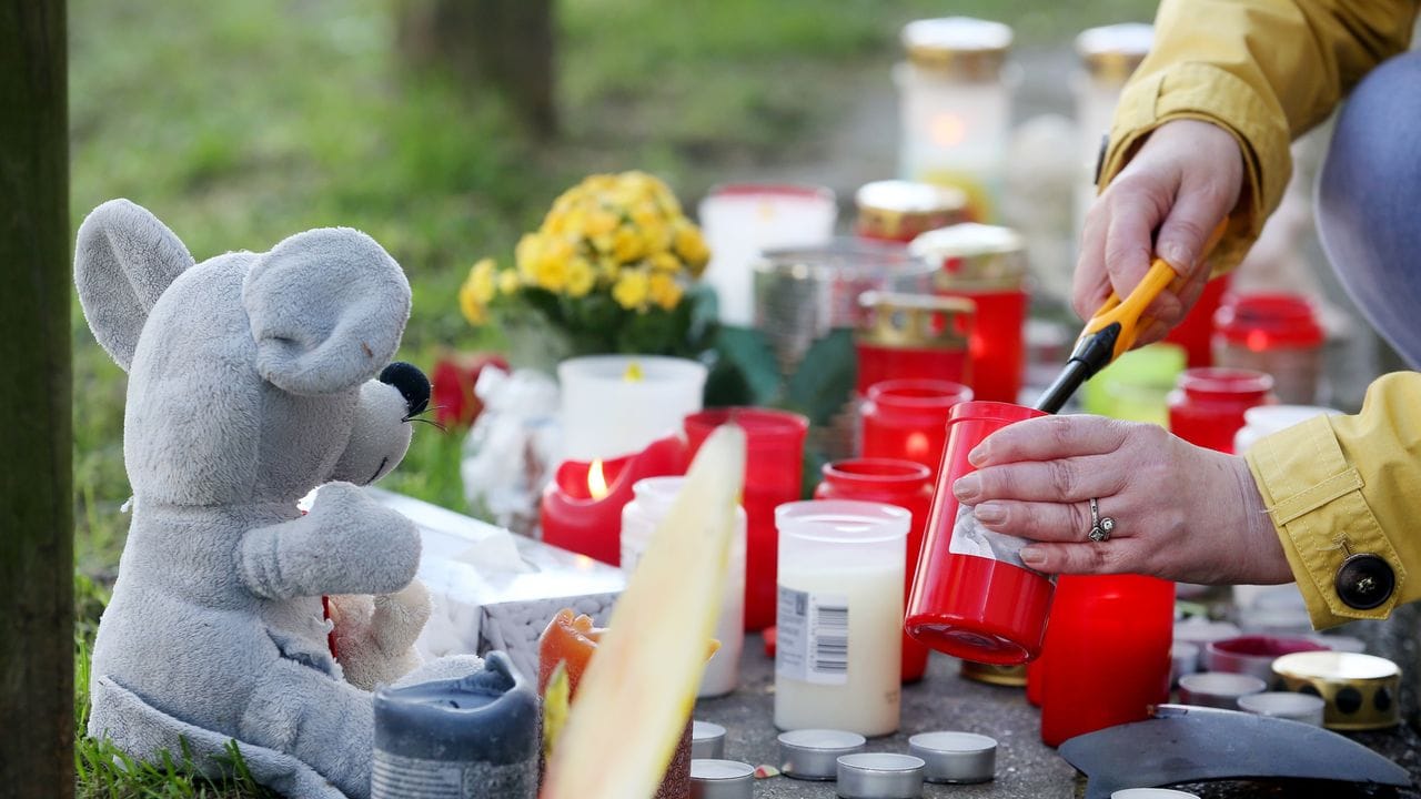 Eine Anwohnerin zündet am Parkhaus eine Kerze für die toten Teenager an.