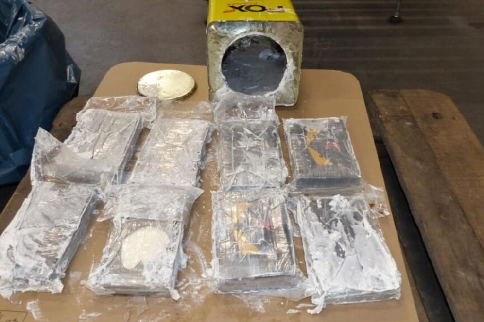 Drogenpakete und eine geöffnete Blechdose liegen auf einem Tisch (Archivbild): Im Februar 2021 war versucht worden, auf diese Weise 16 Tonnen Kokain über den Hamburger Hafen einzuschmuggeln.