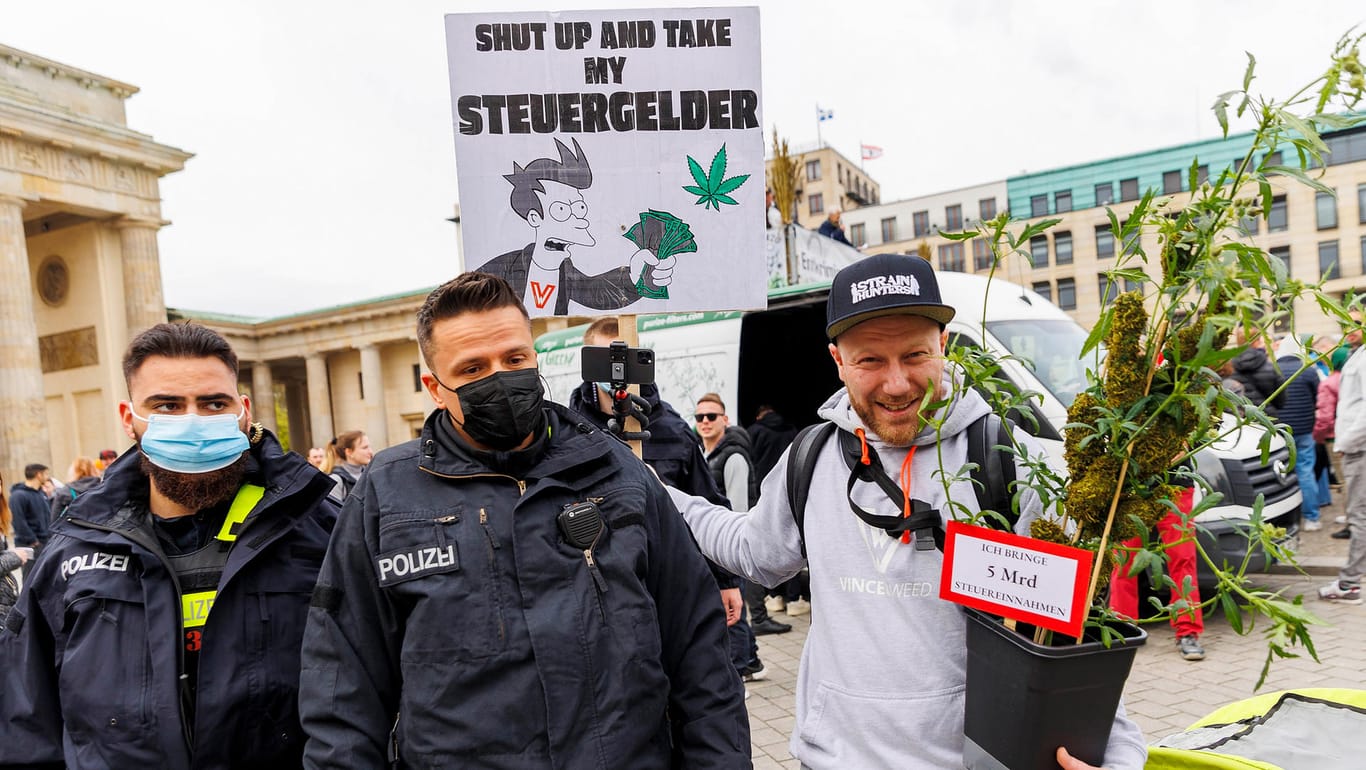 Zwei Polizisten stehen neben einem Teilnehmer, der eine Hanfpflanze im Arm hält, während der Demonstration für die Legalisierung von Cannabis vor dem Brandenburger Tor: Insgesamt rund 1.400 Personen nahmen Teil.