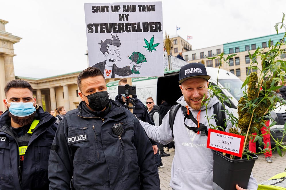 Zwei Polizisten stehen neben einem Teilnehmer, der eine Hanfpflanze im Arm hält, während der Demonstration für die Legalisierung von Cannabis vor dem Brandenburger Tor: Insgesamt rund 1.400 Personen nahmen Teil.