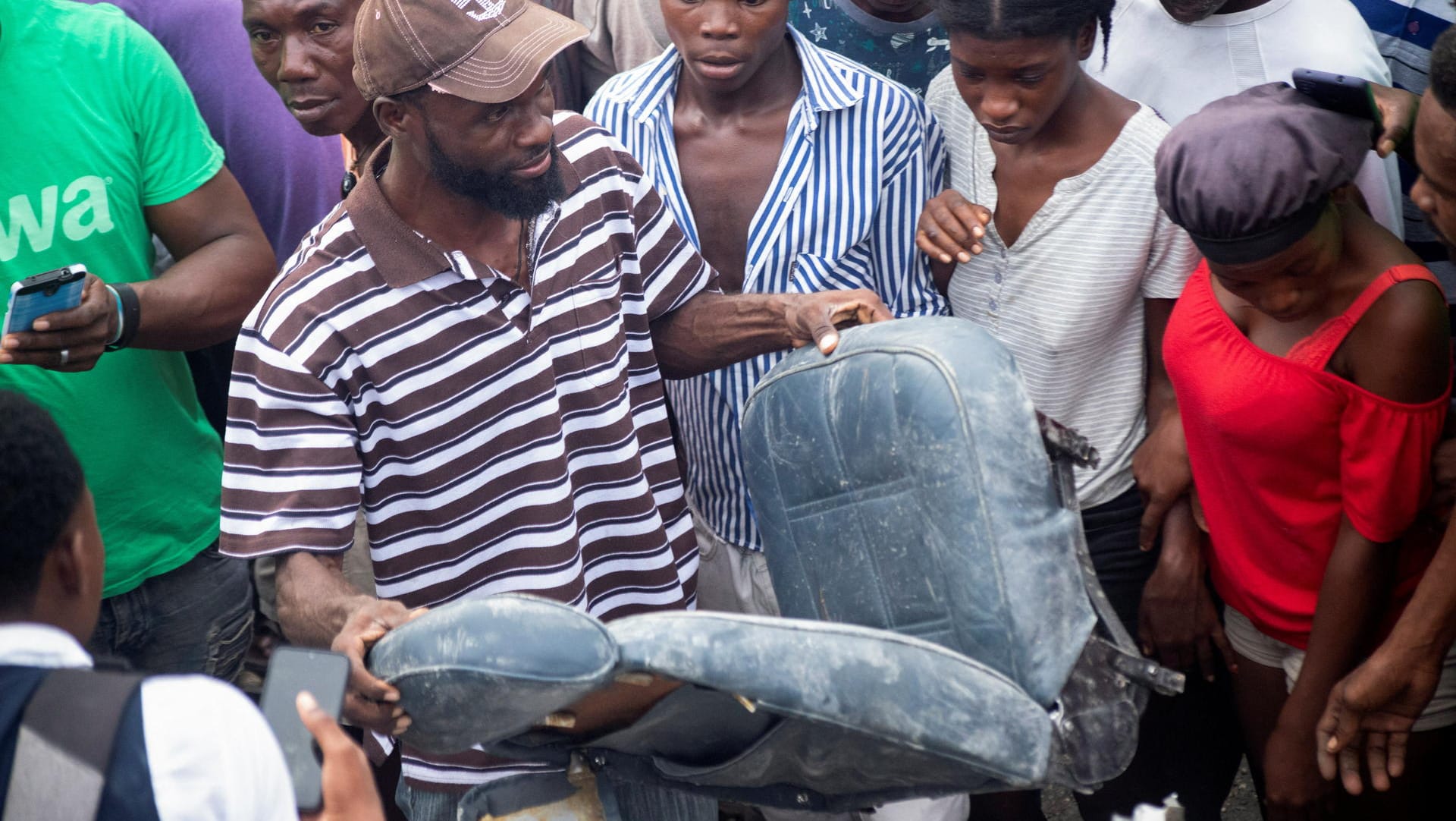 Haiti: Ein Mann hält einen Sitz aus dem Flugzeug, das auf einer Straße in der Hauptstadt Port-au-Prince abgestürzt ist. Haiti: Ein Mann hält einen Sitz aus dem Flugzeug, das auf einer Straße in der Hauptstadt Port-au-Prince abgestürzt ist.