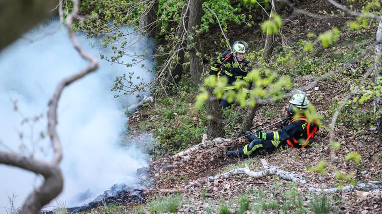 Einsatzkräfte der Feuerwehr löschen unter schweren Bedingungen am Mittwochabend einen Waldbrand an einem Hang: Stundenlang kämpften 80 Kräfte gegen die Flammen.