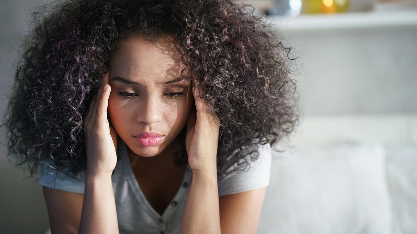 Eine Frau hält sich die Schläfen: Starke Kopfschmerzen können beunruhigend sein.