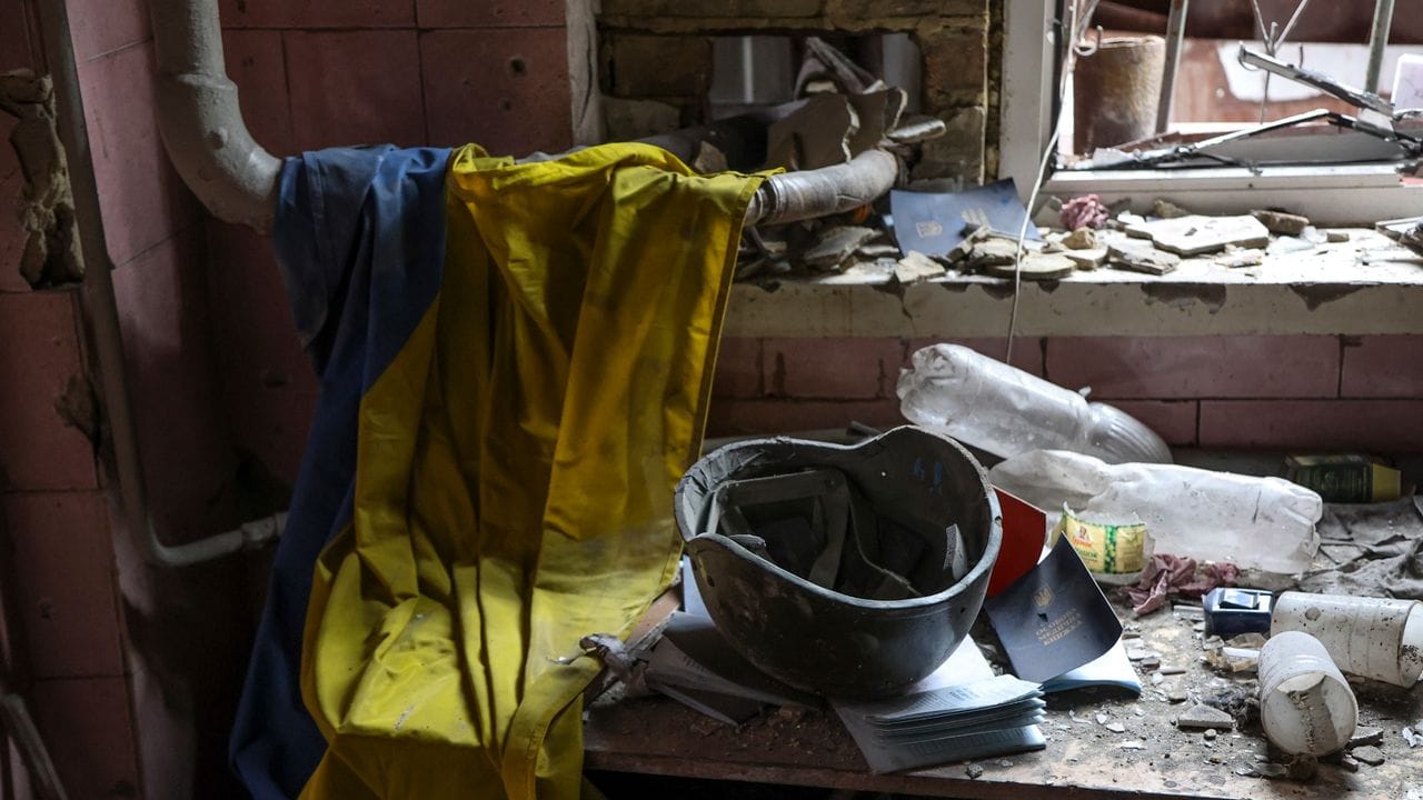 Eine ukrainische Flagge, ein Militärhelm und Dokumente liegen auf einem Tisch in einem zerstörten Teil einer Fabrik in Mariupol. Eine ukrainische Flagge, ein Militärhelm und Dokumente liegen auf einem Tisch in einem zerstörten Teil einer Fabrik in Mariupol.