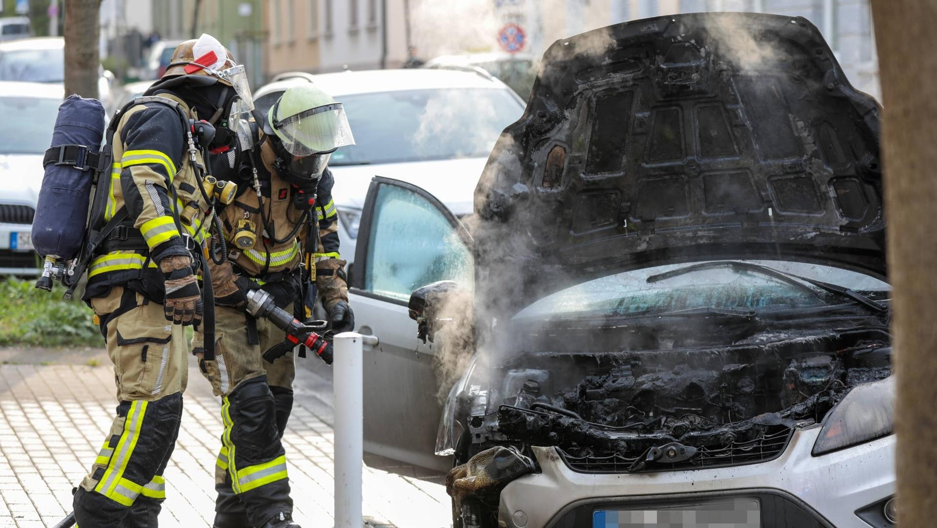 Zwei Löschkräfte der Feuerwehr vor einem Auto (Symbolfoto): In Berlin dauerte ein Löscheinsatz der Feuerwehr stundenlang an. Zwei Löschkräfte der Feuerwehr vor einem Auto (Symbolfoto): In Berlin dauerte ein Löscheinsatz der Feuerwehr stundenlang an.