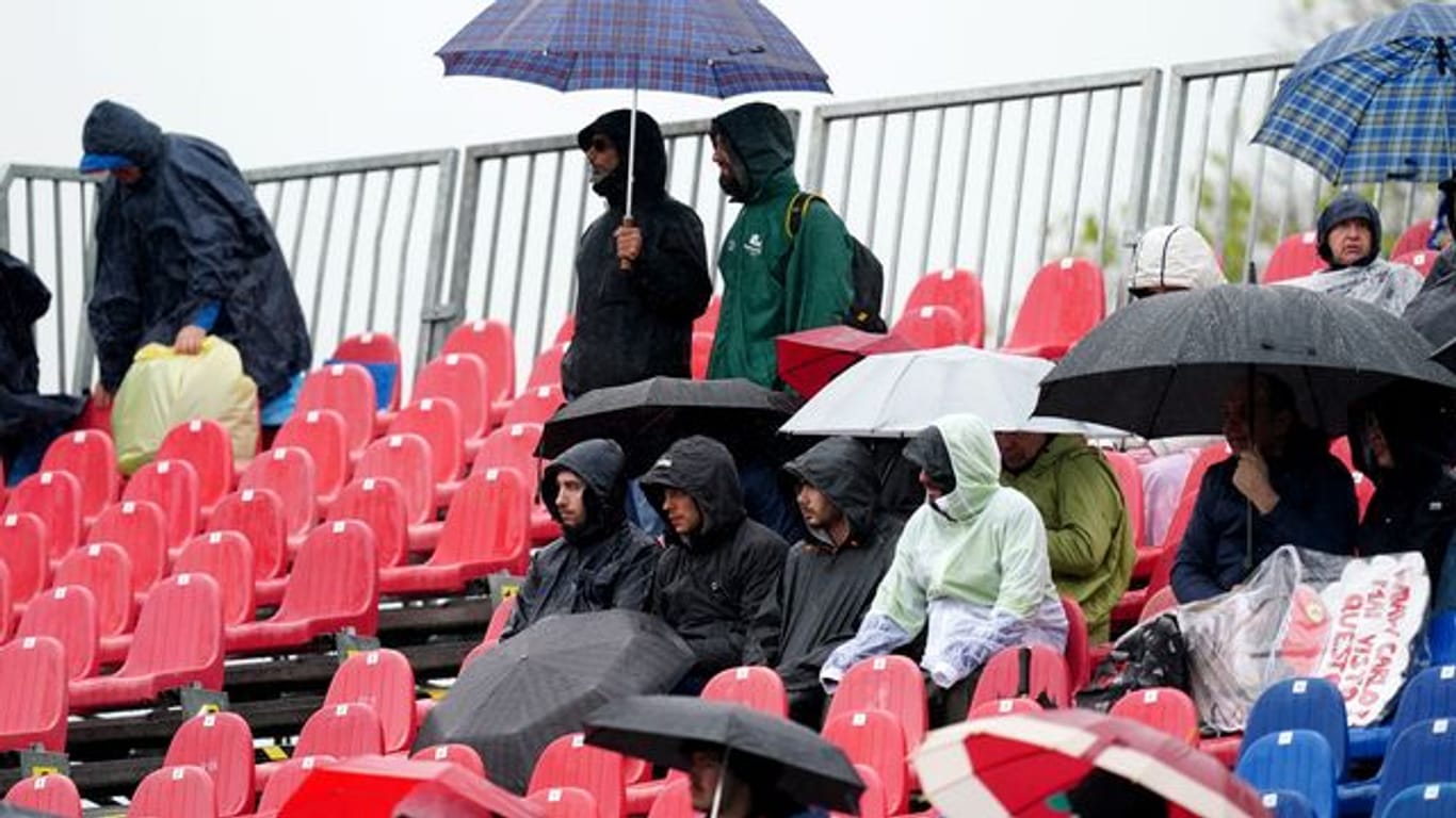 Fans sitzen während des Freien Trainings mit Regenschirmen auf der Tribüne.