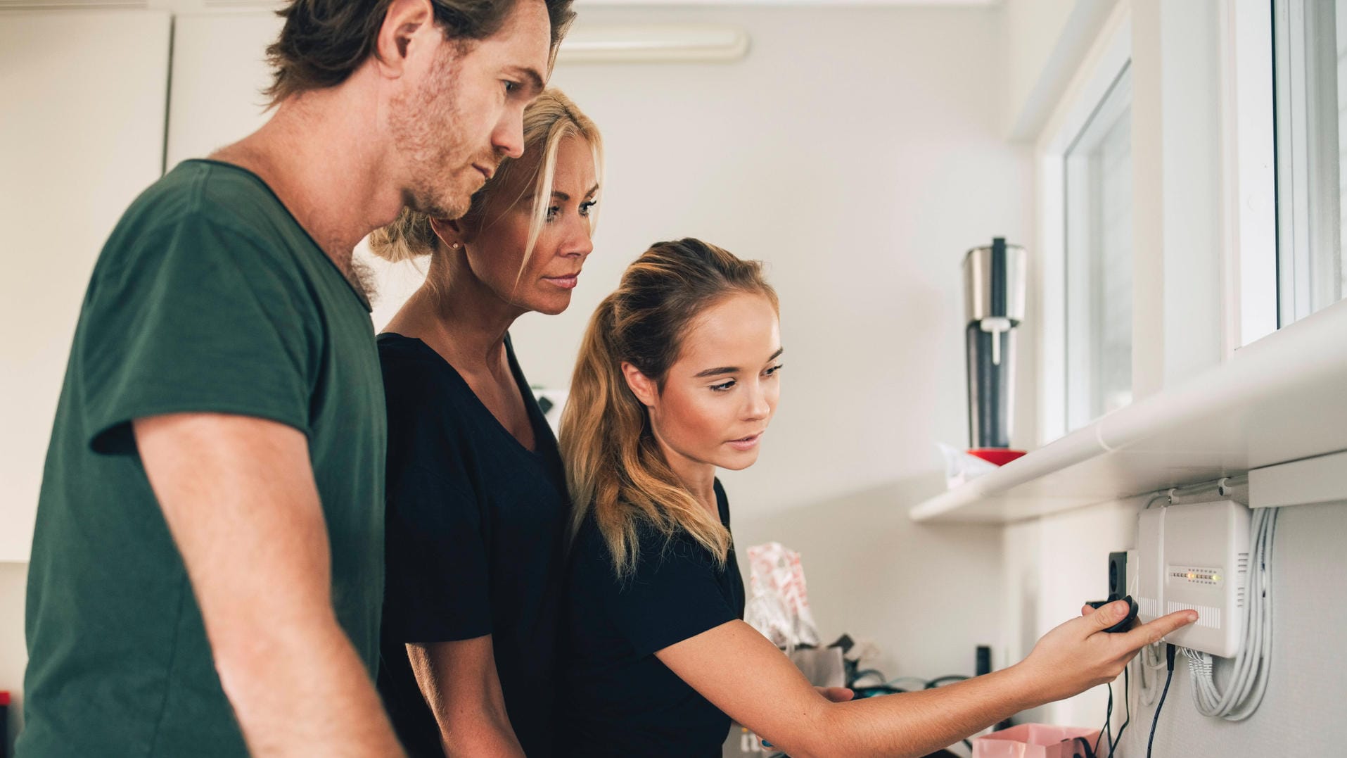 Teenage girl pointing at equipment mounted on wall to parents at home , model released, property released Copyright: xMa