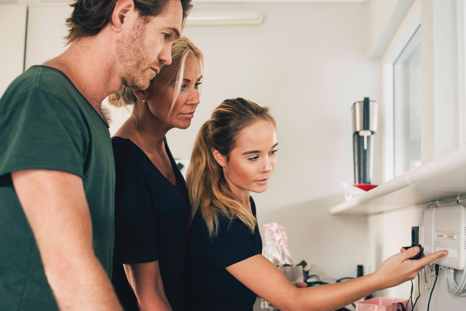 Teenage girl pointing at equipment mounted on wall to parents at home , model released, property released Copyright: xMa