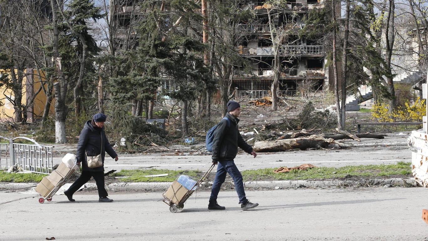 Zwei Menschen gehen vor zerstörten Gebäuden in Mariupol entlang: Ein Fluchtkorridor sollte den Menschen aus der Hafenstadt die Flucht ermöglichen.