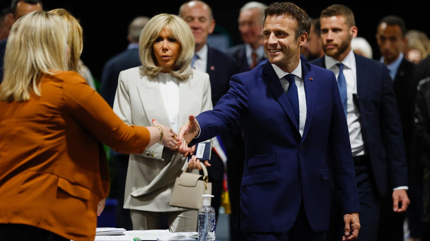 Emmanuel Macron begrüßt eine Wahlhelferin in einem Wahllokal.