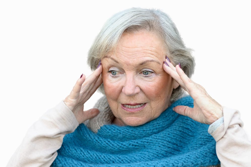 Eine ältere Frau greift sich an die Schläfen. Neben Sehstörungen und einem vorübergehenden Taubheitsgefühl können auch Gedächtnisstörungen Vorboten für einen Schlaganfall sein.