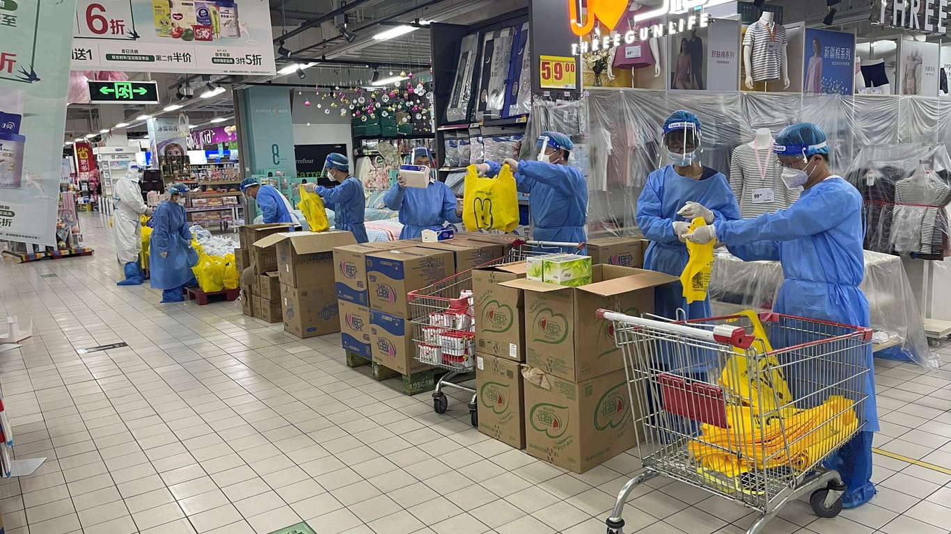 Supermarktmitarbeiter arbeiten in Schutzkleidung: Die Supermarktregale sind an viele Stellen leergekauft.