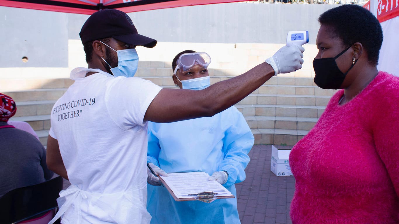 Bei einer Frau in Johannesburg wird Fieber gemessen (Symbolbild): in Südafrika steigen die Infektionszahlen wieder.