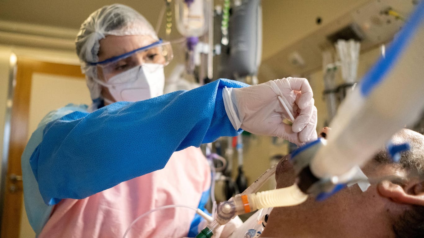 Eine Pflegerin reinigt den Beatmungsschlauch eines Corona-Patienten (Symbolbild): Noch immer sterben fast 300 Menschen in Deutschland pro Tag an den Folgen einer Infektion.