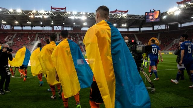 Schachtjor-Spieler (l) betreten für ein Benefizspiel gegen Olympiakos Piräus den Rasen.