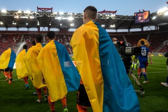 Schachtjor-Spieler (l) betreten für ein Benefizspiel gegen Olympiakos Piräus den Rasen.