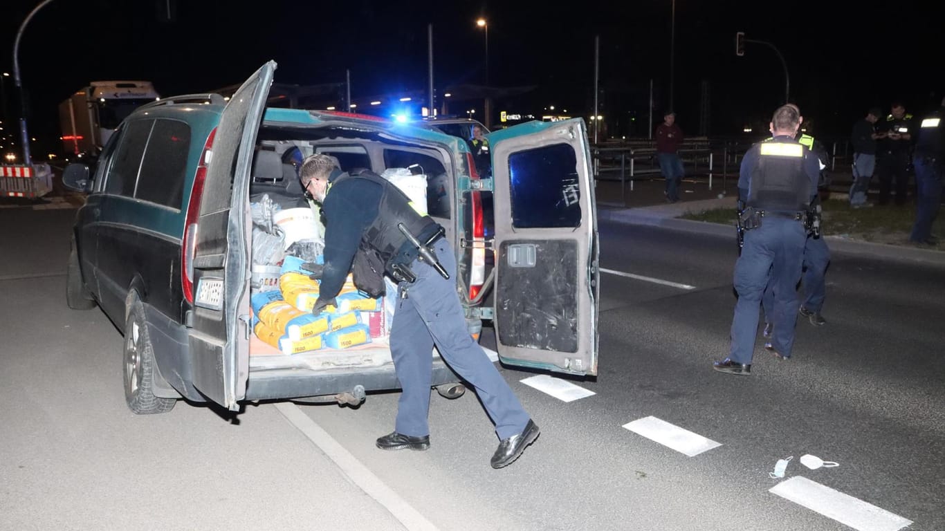Polizeikräfte beladen den Transporter wieder mit Fliesenkleber: Um den Wagen bergen zu können, mussten diese vorher aus dem Transporter geholt werden.