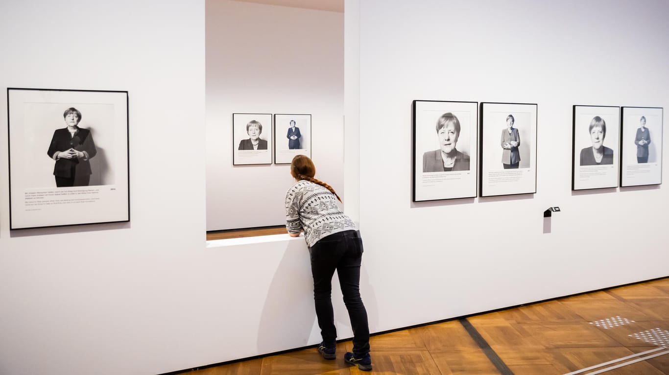 Eine Person lehnt bei einem Presserundgang durch die Ausstellung: Die Fotos zeigen die Entwicklung der Politikerin Merkel.