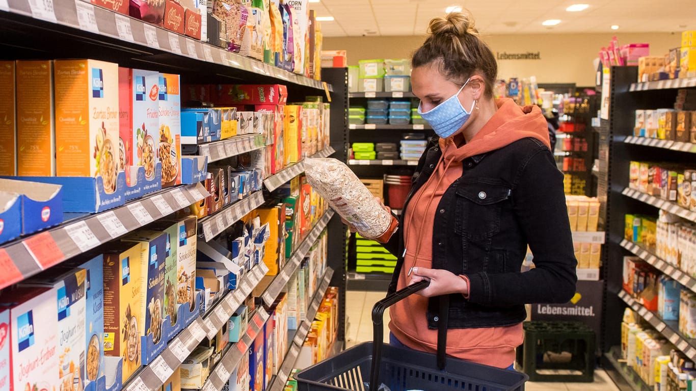 Eine Frau mit Mund-Nasen-Schutz kauft in einem Supermarkt ein (Symbolbild): Experten raten sich in geschlossenen Räumen weiterhin zu schützen.