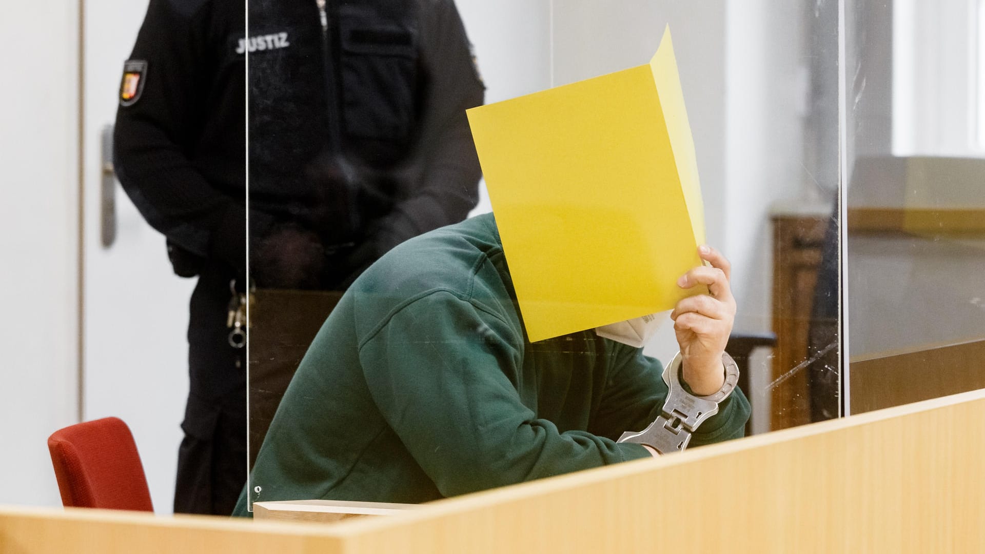 Der Angeklagte verbirgt sein Gesicht hinter einem Aktenordner: Die Urteilsbegründung lautet "Mord aus niedrigen Beweggründen". Der Angeklagte verbirgt sein Gesicht hinter einem Aktenordner: Die Urteilsbegründung lautet "Mord aus niedrigen Beweggründen".