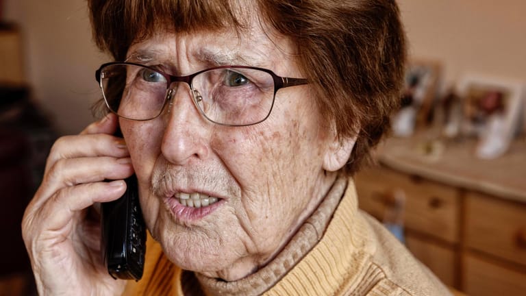 Seniorin zuhause beim Telefonieren schaut unsicher (Symbolbild): Neben dem Enkeltrick gibt es auch zahlreiche andere Maschen, die mittlerweile durch professionelle Call-Centren ausgeführt werden.