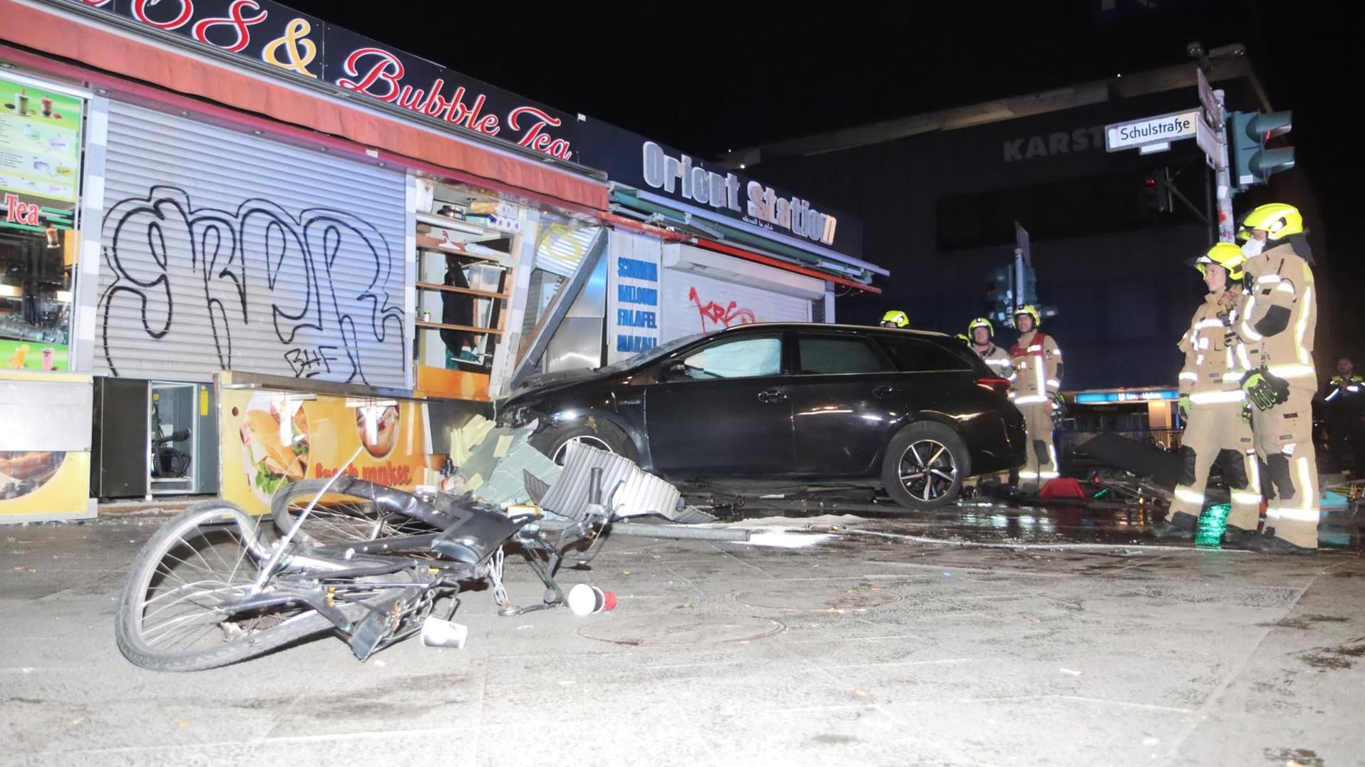 Feuerwehrleute stehen um den Unfallwagen, der in den Kiosk krachte: Drei Männer wurden bei dem Unfall verletzt.