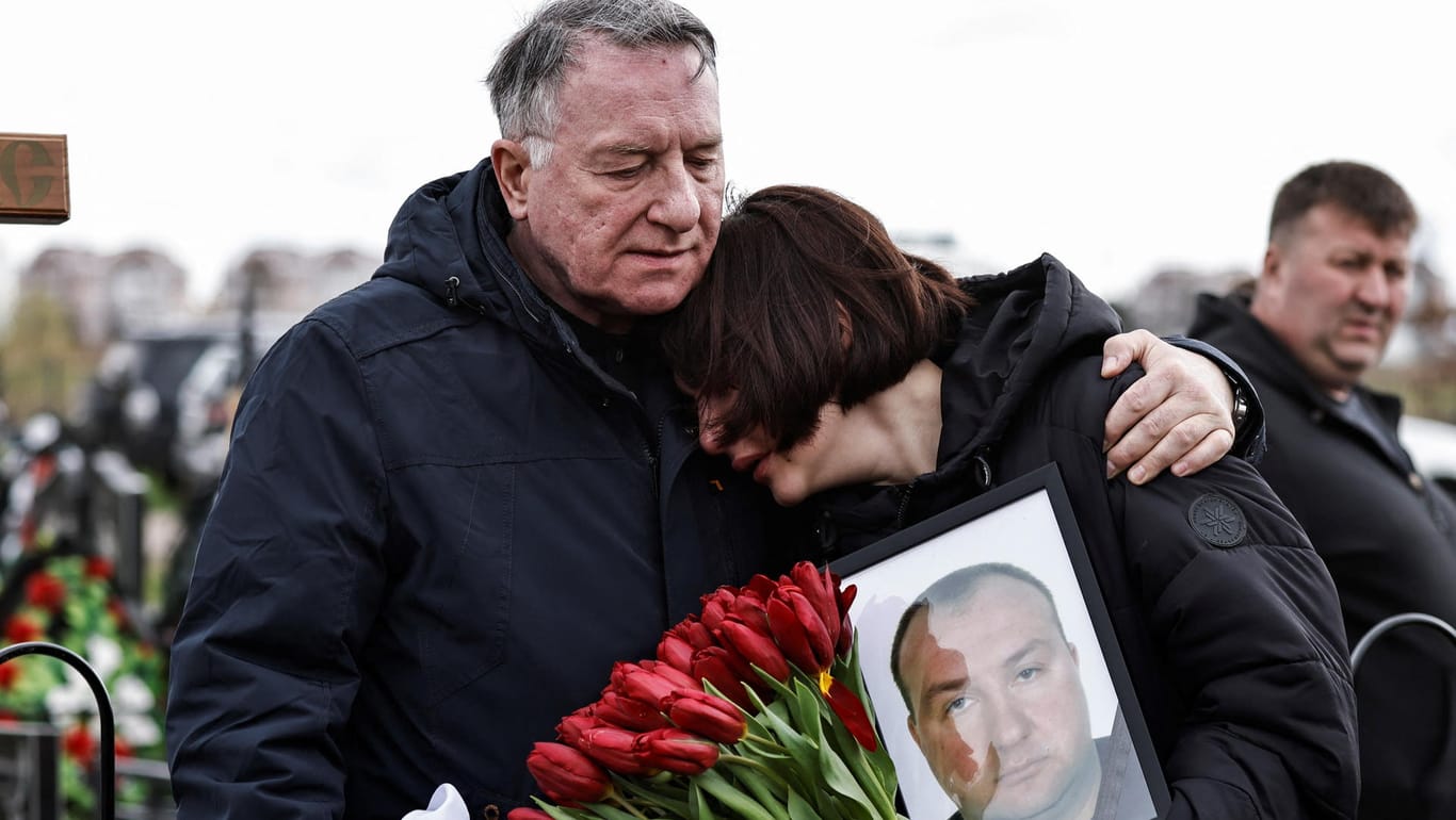Beerdigung auf dem Friedhof von Butscha: Maria hält ein Foto ihres Vaters Yurii Alekseev, der nach Angaben der Familie von russischen Soldaten getötet wurde.