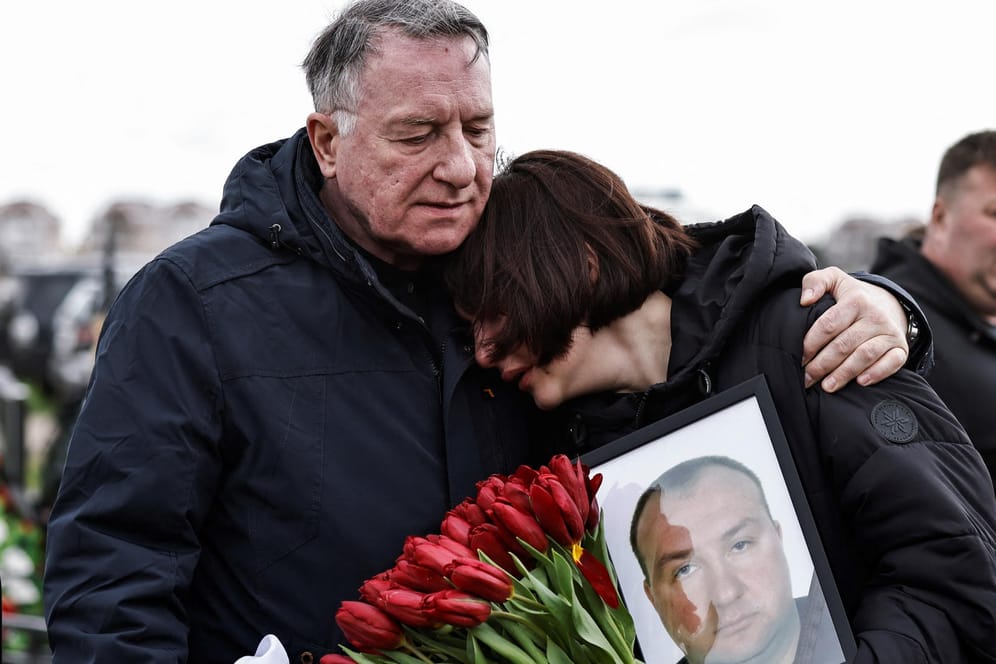 Beerdigung auf dem Friedhof von Butscha: Maria hält ein Foto ihres Vaters Yurii Alekseev, der nach Angaben der Familie von russischen Soldaten getötet wurde.