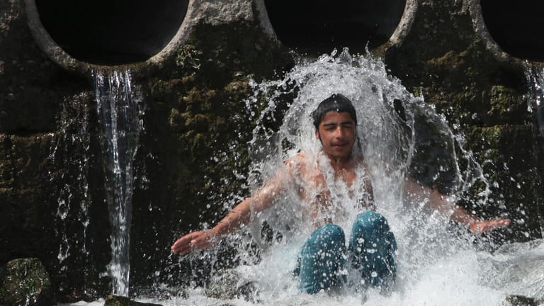 Im pakistanischen Peshawar kühlt sich ein Junge in einem Bach ab: Hunderte Millionen Menschen leiden unter der Hitzewelle.