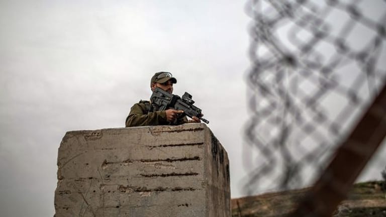 Ein bewaffneter israelischer Soldat hält auf seinem Posten in Hebron Wache.