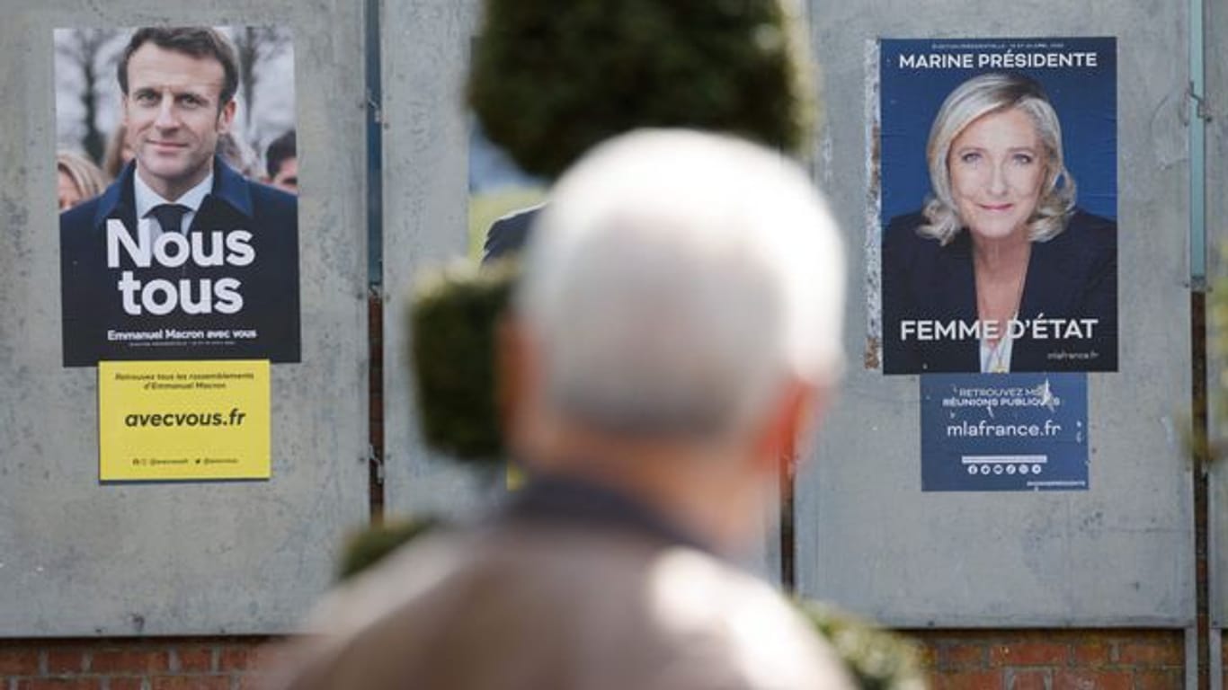 Ein Mann geht an Wahlkampfplakaten für die Präsidentschaftswahl in Frankreich vorbei.
