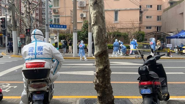 Ein Polizist in Schutzkleidung steht Wache im Jingan-Bezirk in Shanghai.