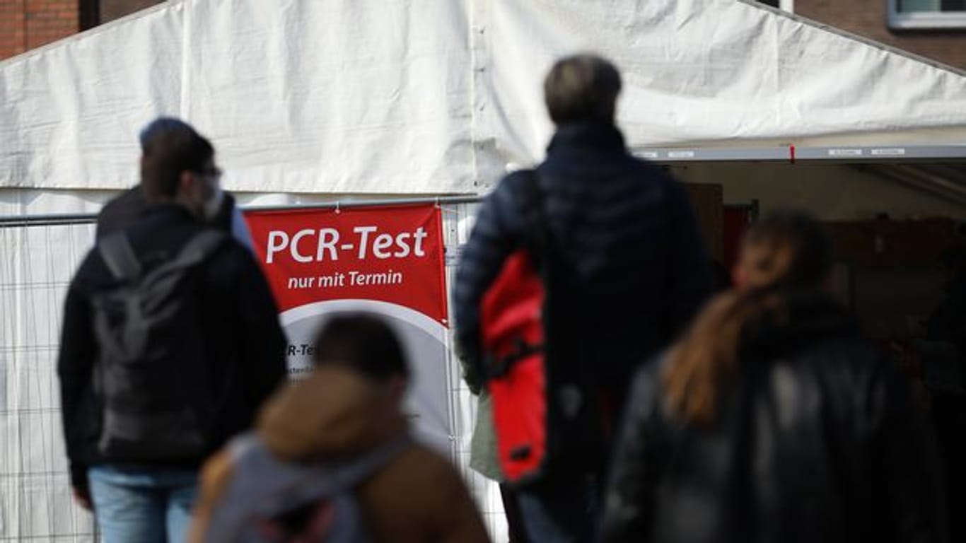Menschen stehen für einen PCR-Test in einer Teststation am Lübecker Holstentor Schlange.