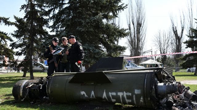 Ukrainische Soldaten während Ermittlungsarbeiten neben einem Fragment einer Tochka-U-Rakete mit der russischen Aufschrift "Für Kinder" nahe des Bahnhofs in Kramatorsk. Ukrainische Soldaten während Ermittlungsarbeiten neben einem Fragment einer Tochka-U-Rakete mit der russischen Aufschrift "Für Kinder" nahe des Bahnhofs in Kramatorsk.