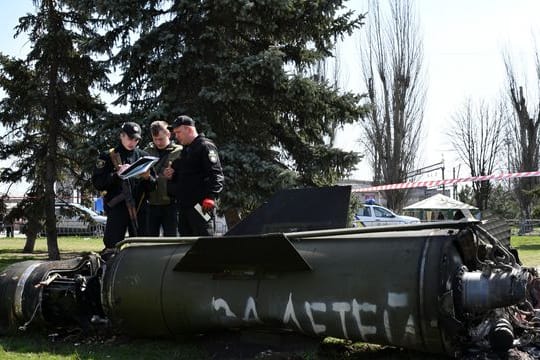 Ukrainische Soldaten während Ermittlungsarbeiten neben einem Fragment einer Tochka-U-Rakete mit der russischen Aufschrift "Für Kinder" nahe des Bahnhofs in Kramatorsk.