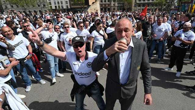 Eintracht-Präsident Peter Fischer (r) trinkt mit den angereisten Eintracht-Fans am Treffpunkt Placa de Catalunya ein Bier.