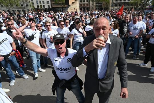 Eintracht-Präsident Peter Fischer (r) trinkt mit den angereisten Eintracht-Fans am Treffpunkt Placa de Catalunya ein Bier.