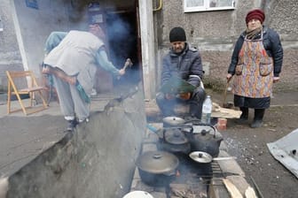 Einwohner kochen in Mariupol im Freien.