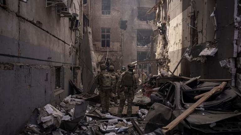 Ukrainische Soldaten gehen zwischen den Trümmern beschädigter Gebäude nach einem russischen Angriff in Charkiw.