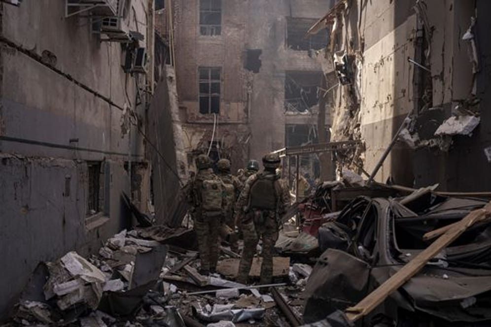 Ukrainische Soldaten gehen zwischen den Trümmern beschädigter Gebäude nach einem russischen Angriff in Charkiw.