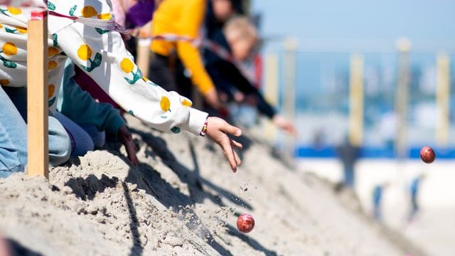 Kinder lassen am Ostersonntag bunte Eier von einer aufgeschütteten Düne am Weststrand von Norderney heruntertrullern. Kinder lassen am Ostersonntag bunte Eier von einer aufgeschütteten Düne am Weststrand von Norderney heruntertrullern.